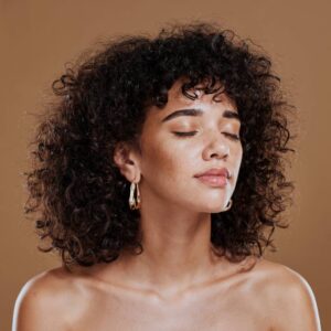 Woman with healthy curly hair and glowing skin after hair restoration.